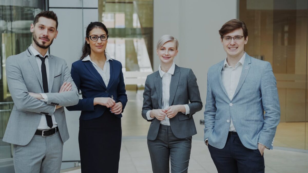 Four business professionals posing confidently in a modern office environment.